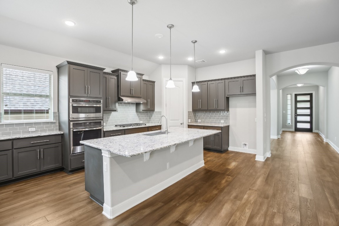 a large kitchen with granite countertop a large counter top stainless steel appliances and wooden floor