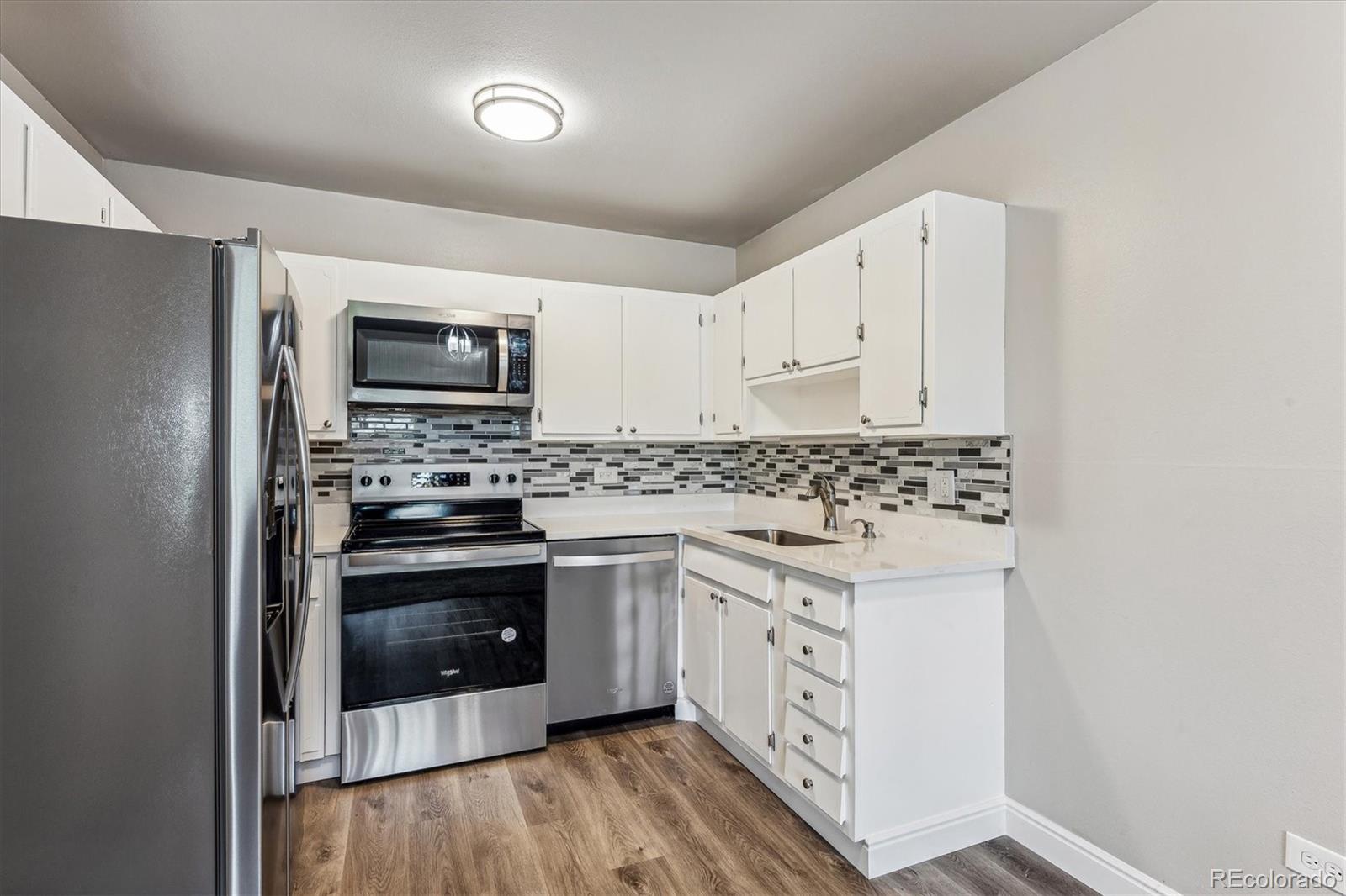 a kitchen with stainless steel appliances a stove a microwave and white cabinets