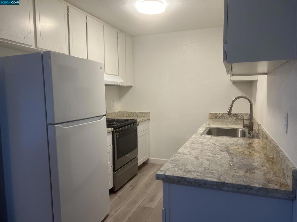 a kitchen with granite countertop a refrigerator and a sink