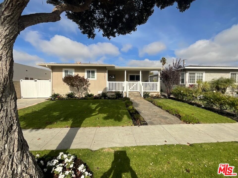 a view of a white house with a yard and potted plants