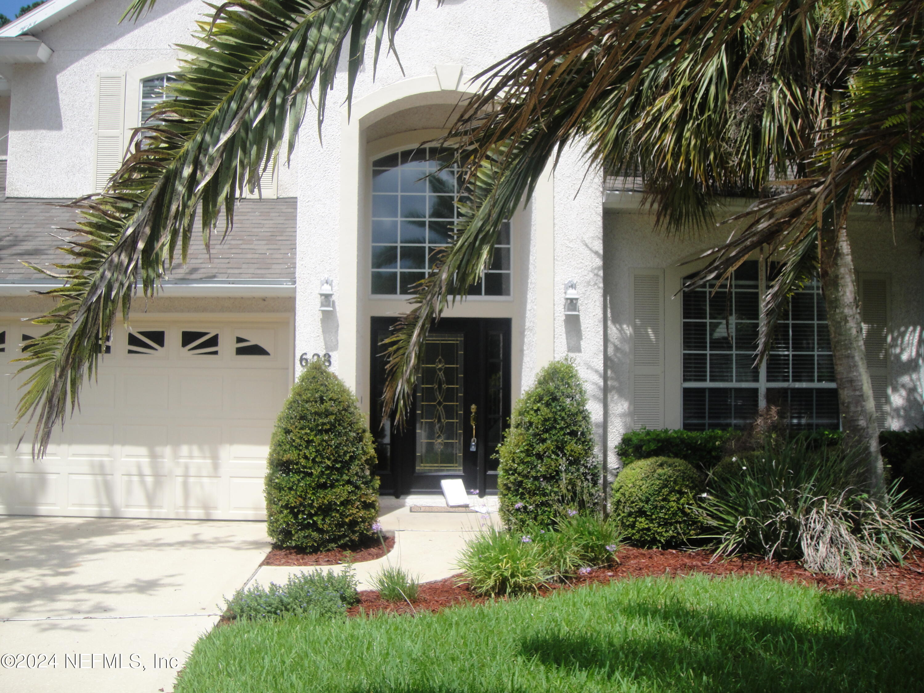 a view of a white house with a small yard and palm trees