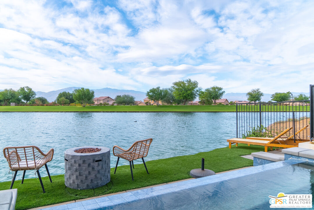 a view of a lake with couches in the patio next to a yard