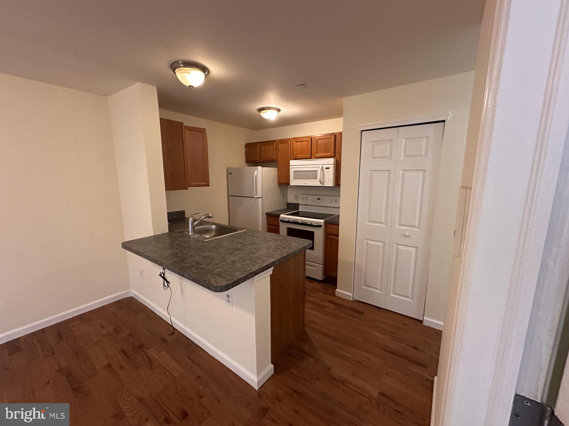 a kitchen with a sink a refrigerator and wooden floor