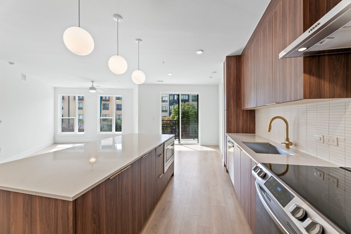 Unit 214 features the "Warm" finish scheme which includes rich walnut-colored cabinetry in the kitchen, brass pulls and fixtures, Carrara marble-style quartz countertops, plus a full Samsung appliance package.