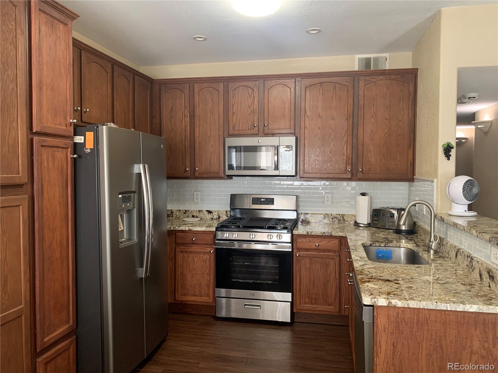 a kitchen with stainless steel appliances granite countertop a refrigerator stove and sink