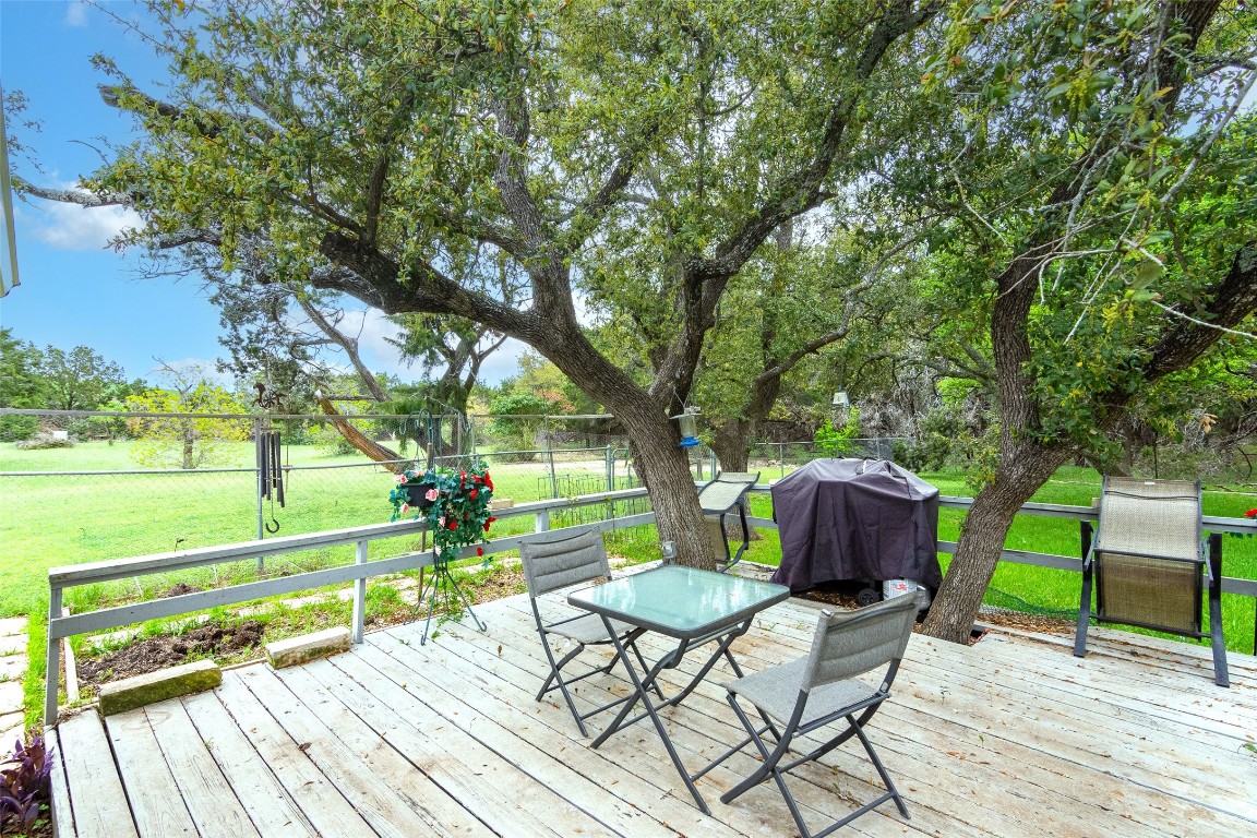 a view of deck with table and chairs and couches with wooden floor and fence