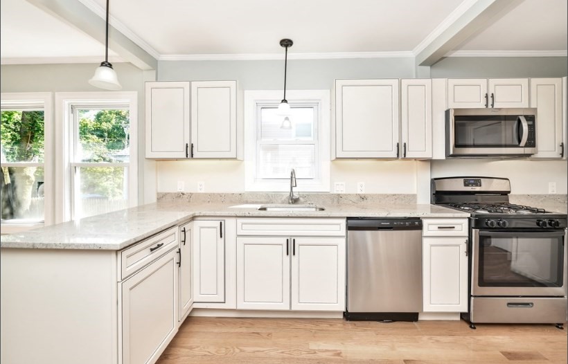 a kitchen with white cabinets white stainless steel appliances and window