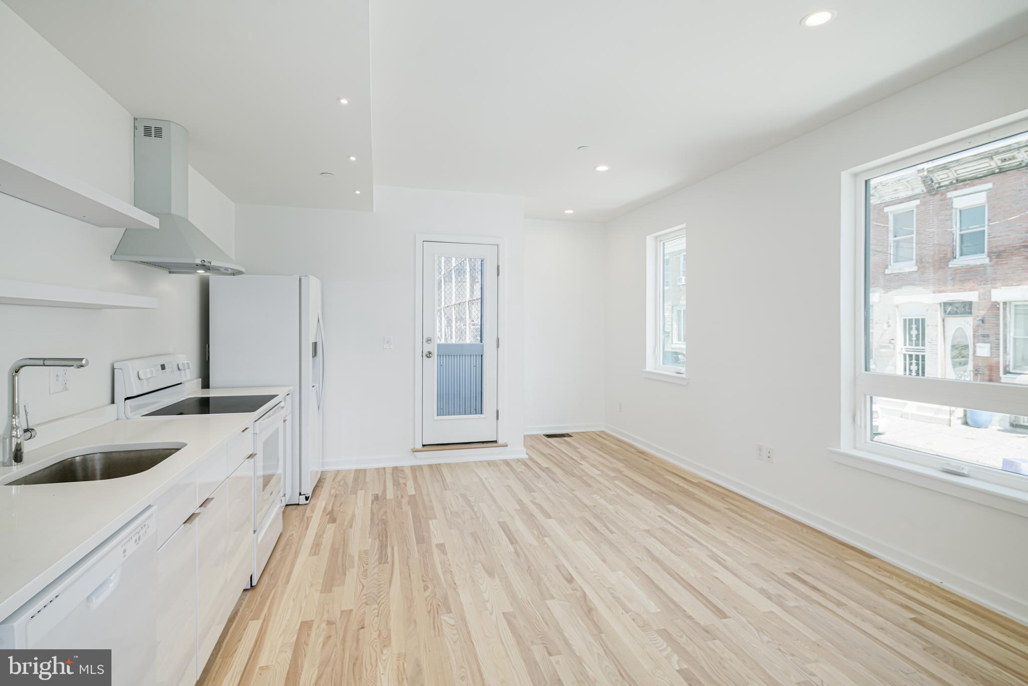 a large kitchen with a lot of white cabinets and wooden floor