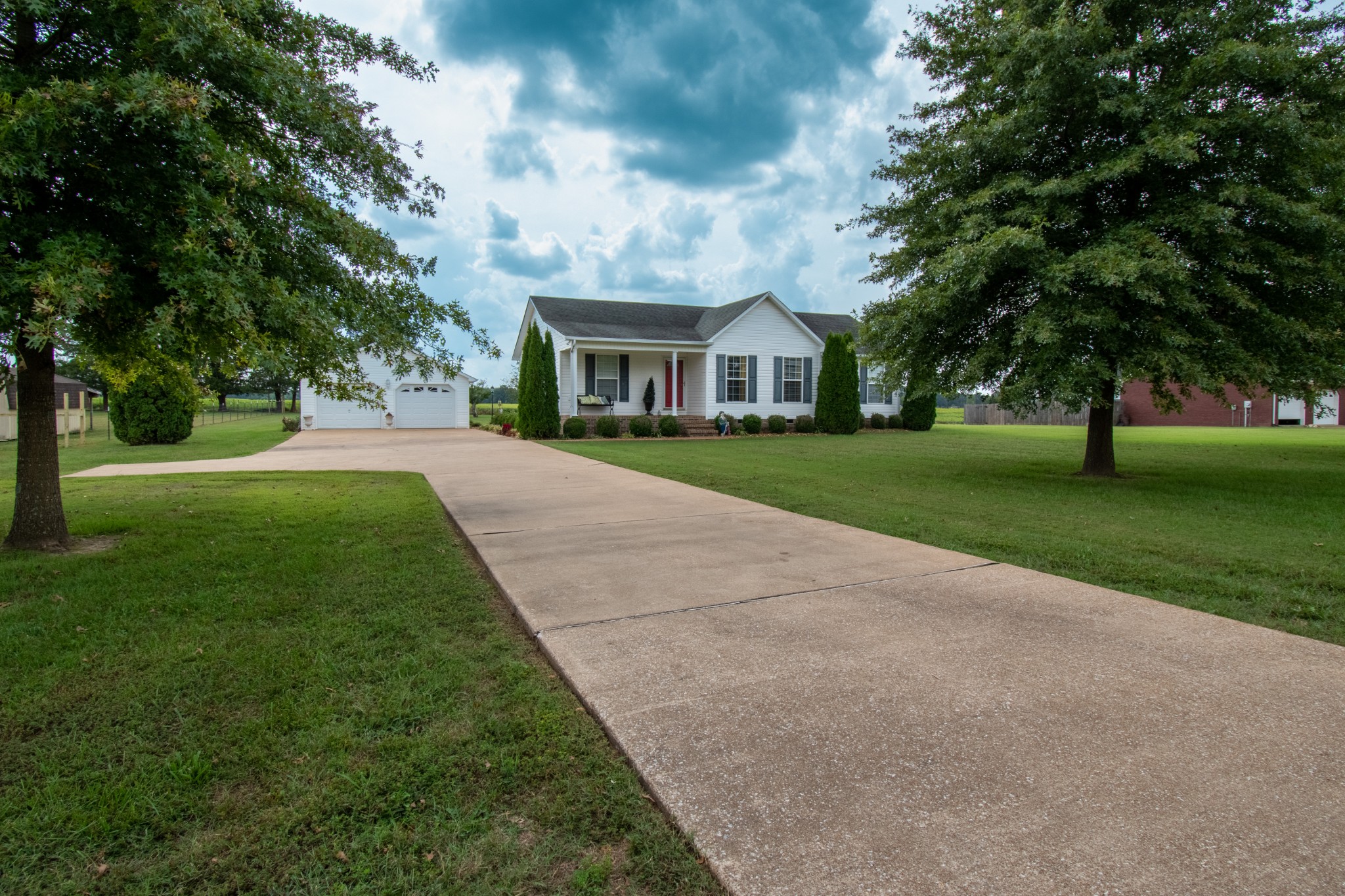 a view of a house with a big yard and large trees