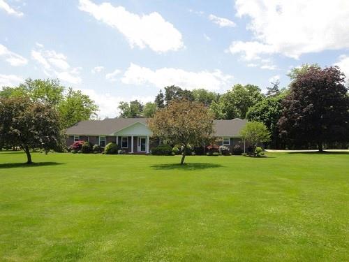 a view of an house with a big yard and large trees