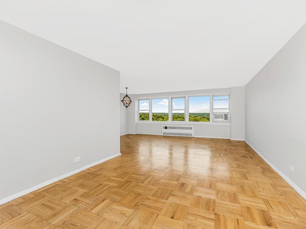 Empty room featuring light parquet floors and radiator heating unit