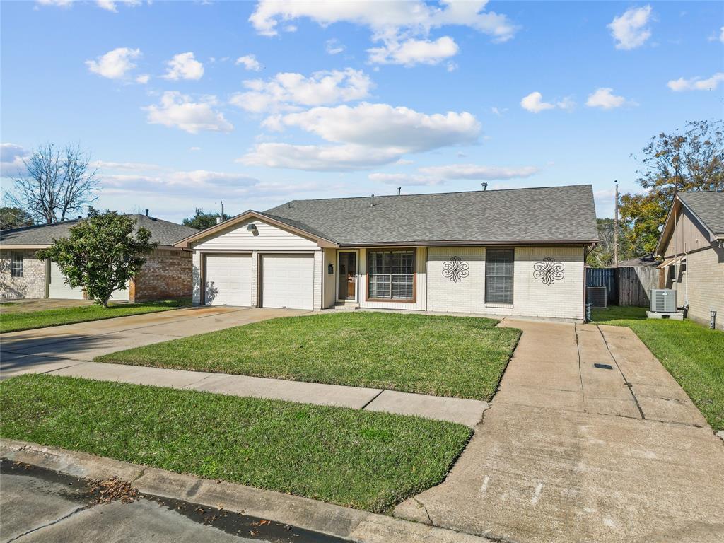 Charming single-story home with a two-car garage, a well-maintained lawn, and dual spacious driveways. The exterior features decorative window accents and a clean, inviting facade. Ideal for comfortable living in a peaceful neighborhood.