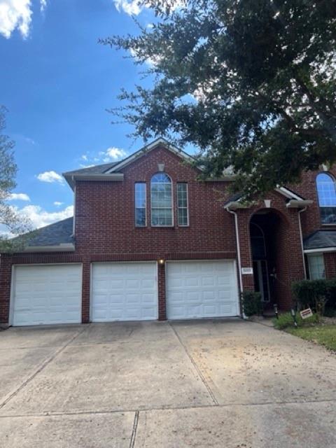 This is a two-story brick home featuring an arched entryway and a 3 car garage.