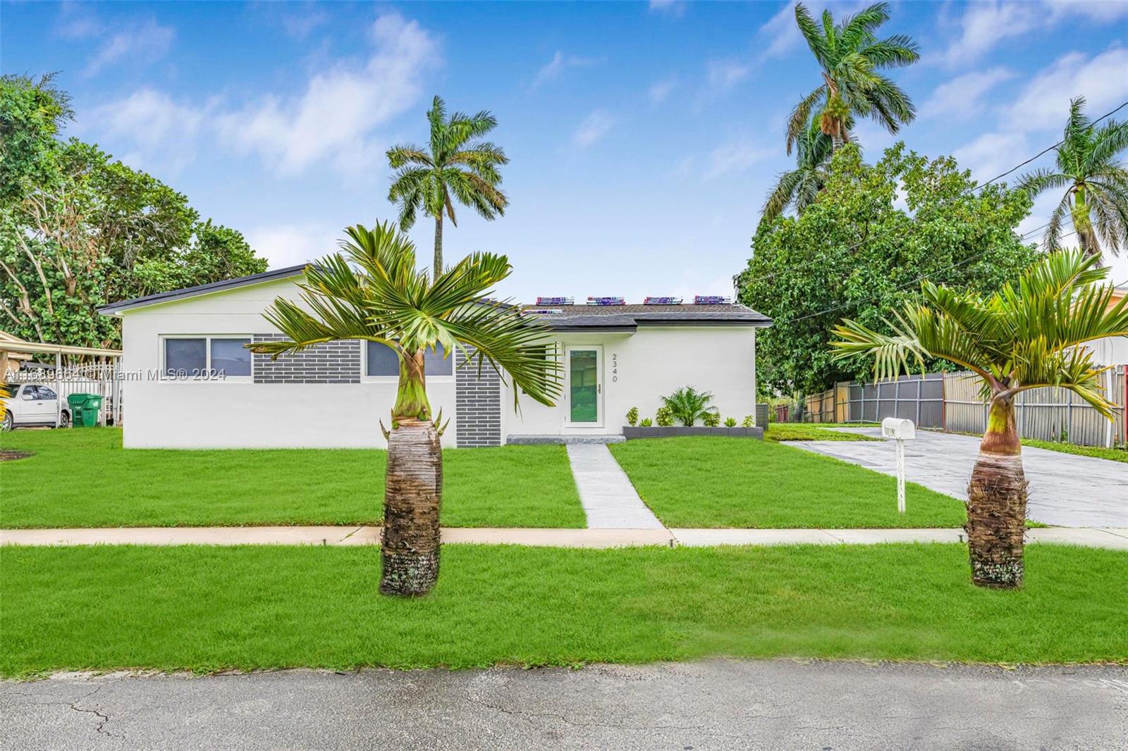 a front view of a house with a garden and trees