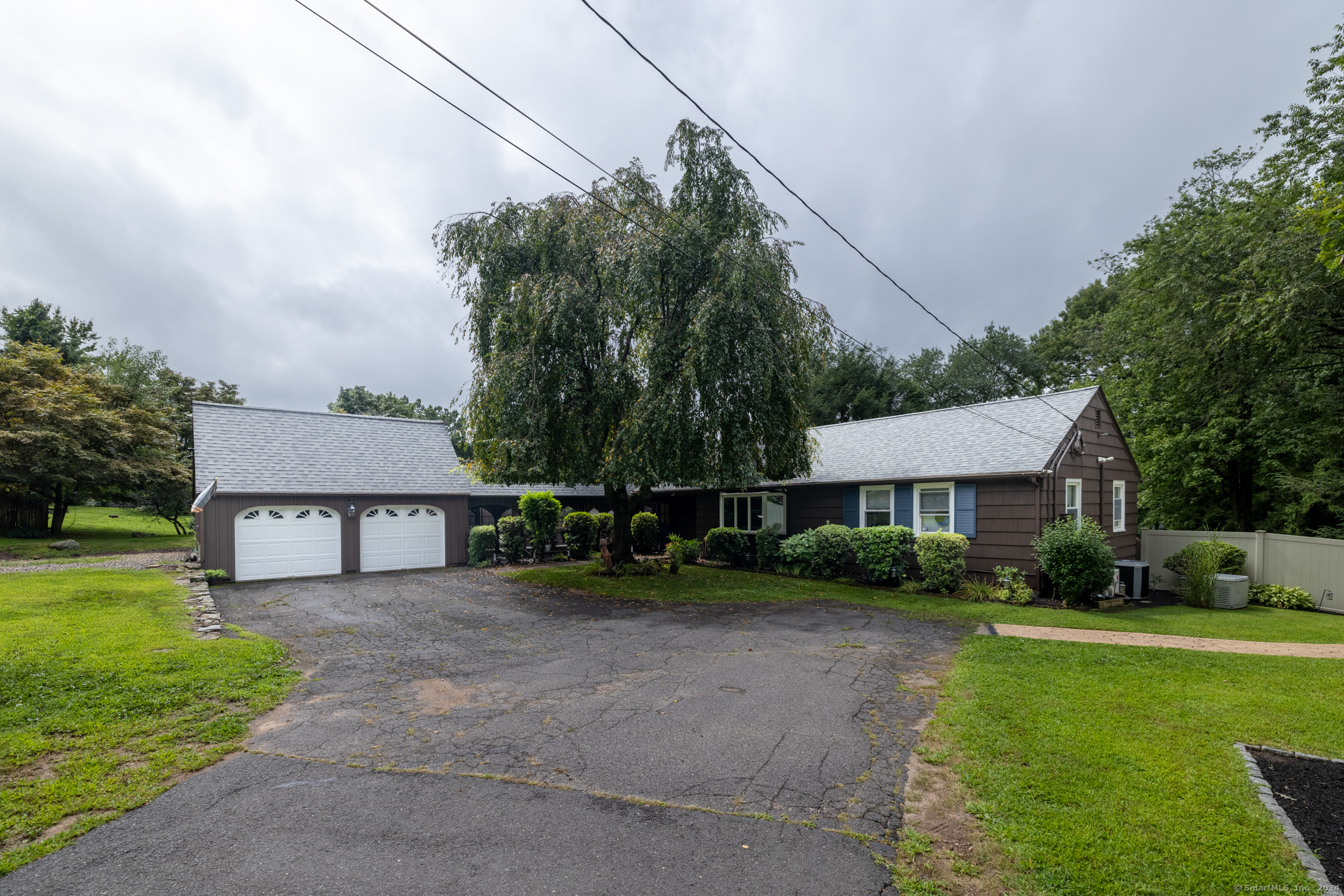 a view of house with a big yard and large trees