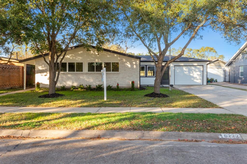 a view of a house with a yard and large tree