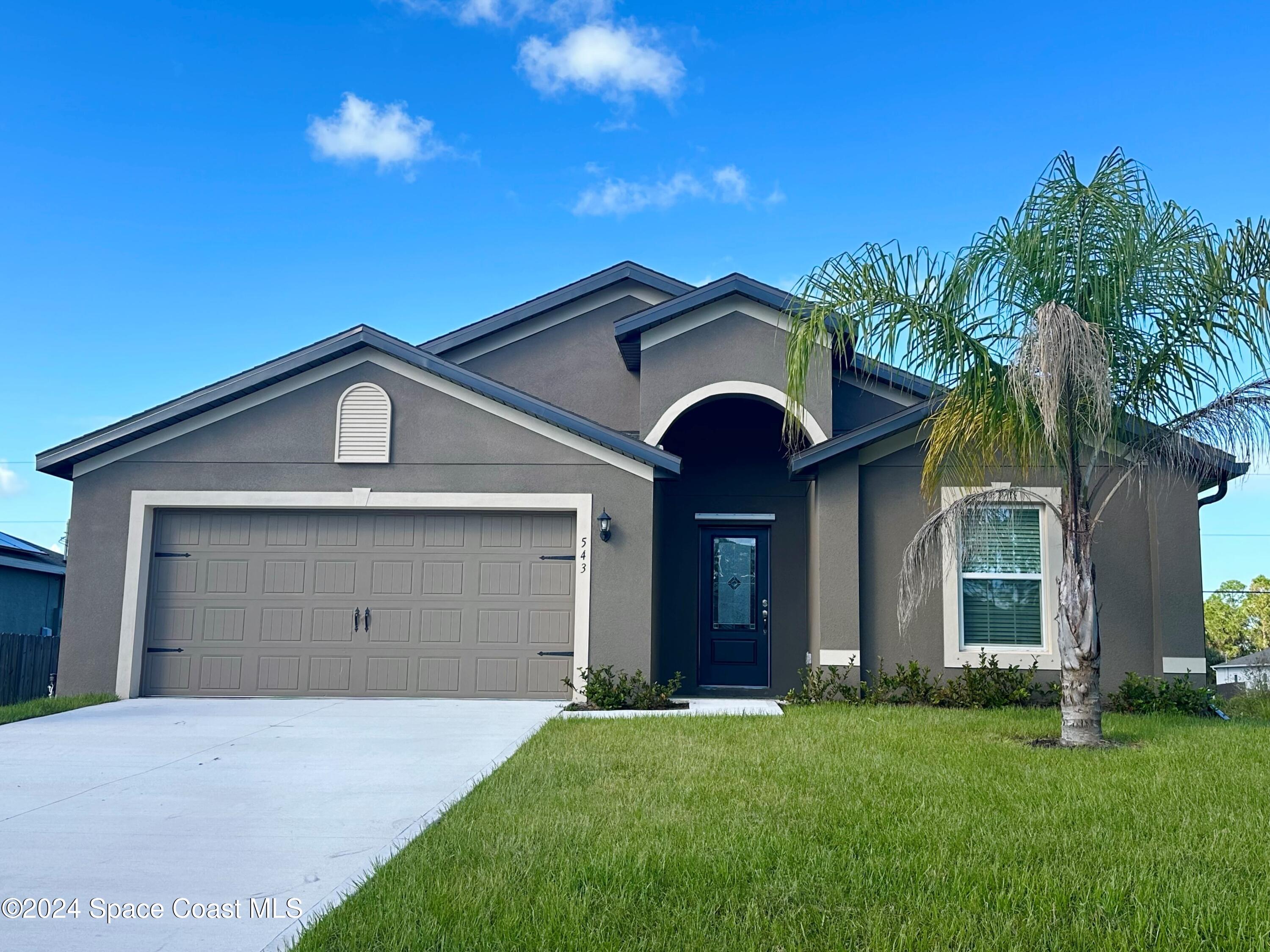 a view of a house with a yard and palm trees