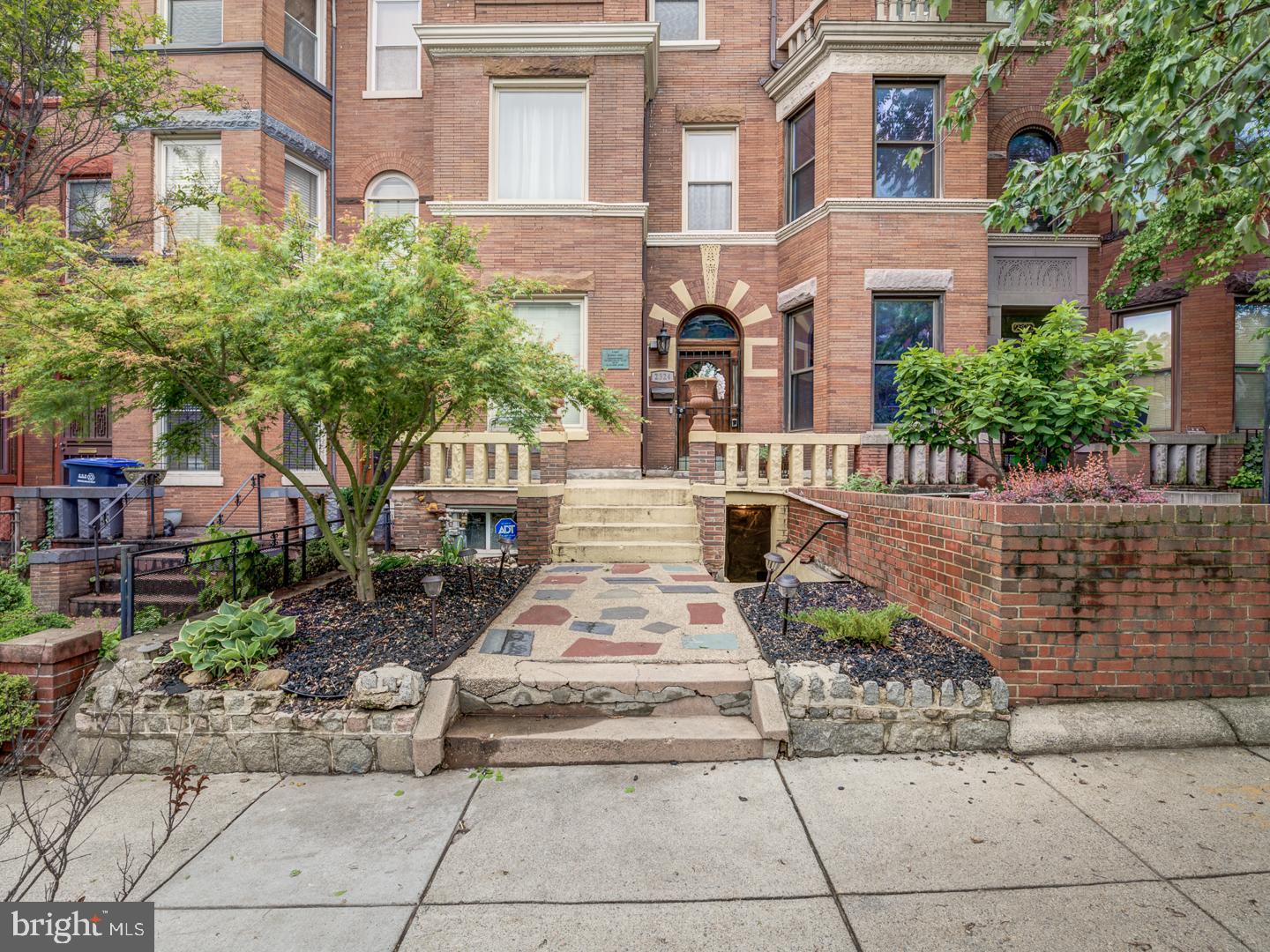 a front view of a multi story residential apartment building with yard and bench