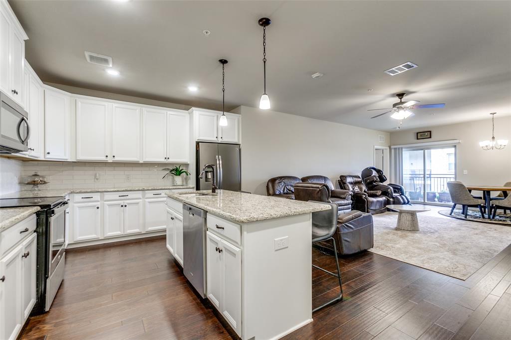 a kitchen that has a lot of white cabinets and wooden floor