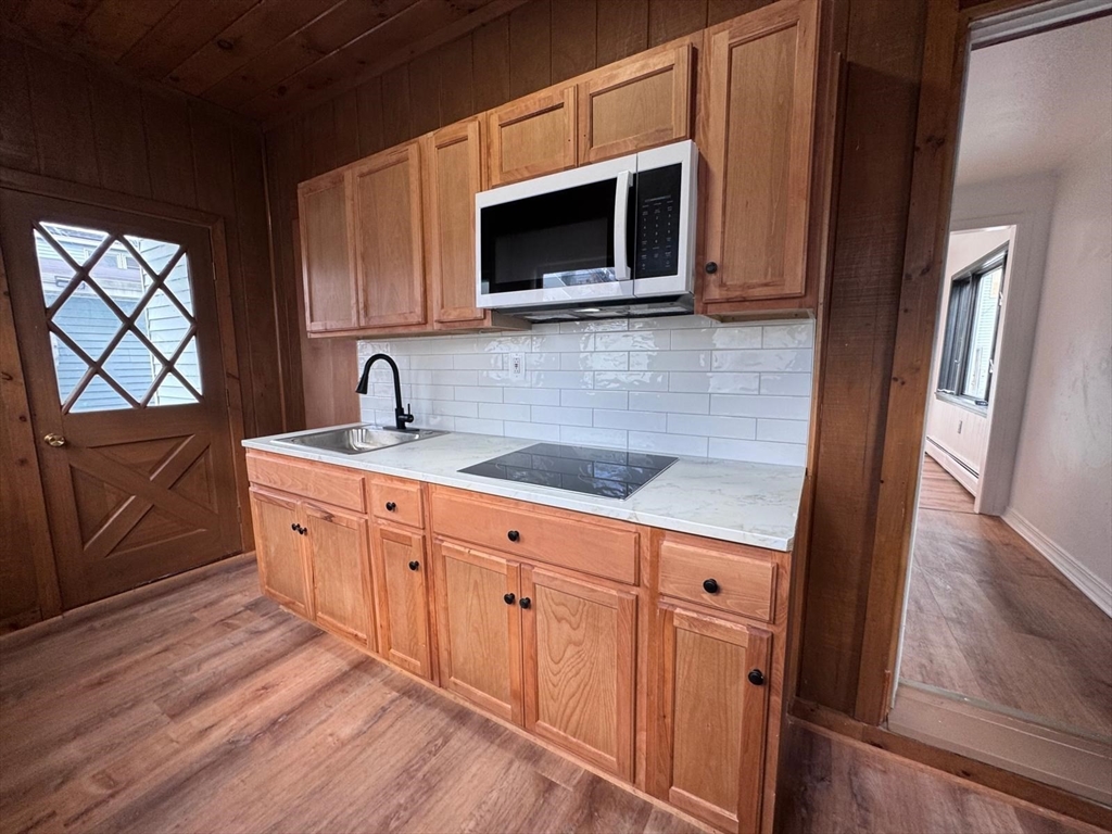 a kitchen with stainless steel appliances granite countertop a sink a microwave cabinets and wooden floor