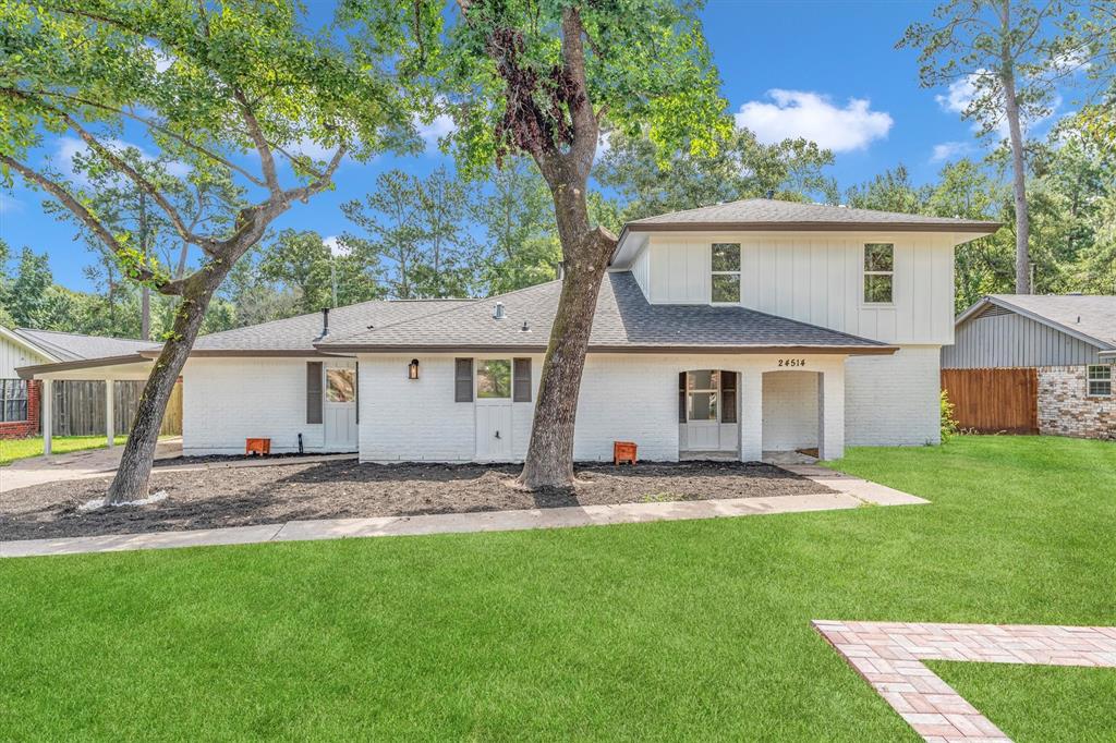 a view of a house with a yard and large tree