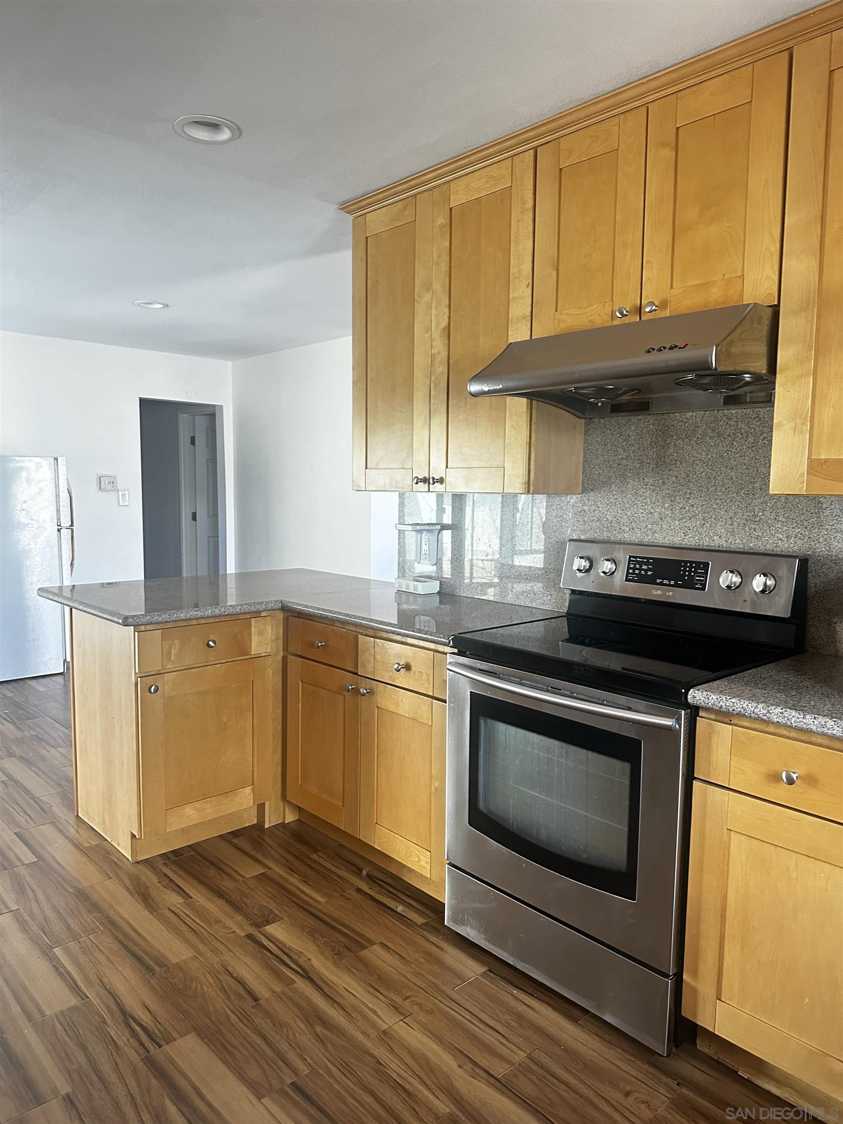 a kitchen with granite countertop wooden cabinets stainless steel appliances and a sink