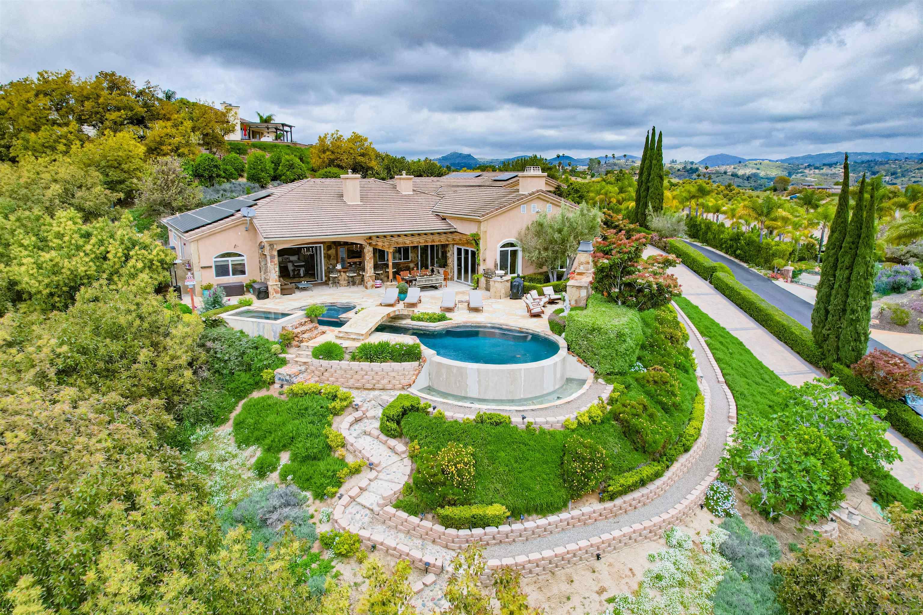 a view of a house with a big yard plants and large tree