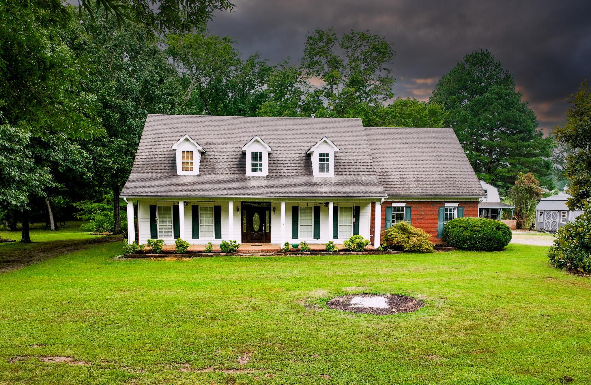 Cape cod home featuring a shed, a front yard, and covered porch