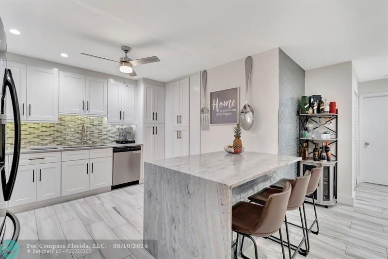 a kitchen with stainless steel appliances kitchen island granite countertop a table chairs and a refrigerator