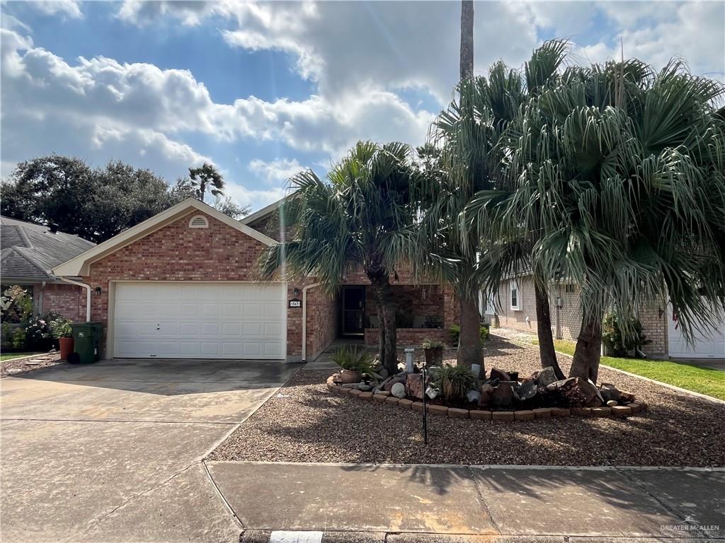 a view of a house with small yard plants and palm trees