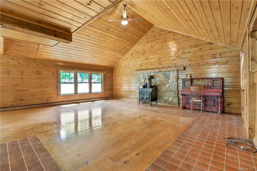 Living Room with Timberline wood stove, wood and tile flooring, vaulted ceiling and ceiling fan