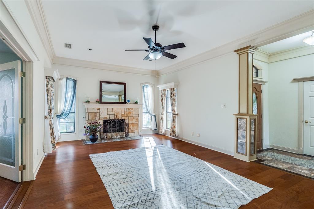 a view of a livingroom with a fireplace a ceiling fan and windows