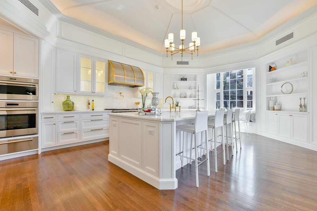 a kitchen with stainless steel appliances a white dining table a sink a stove and wooden floor