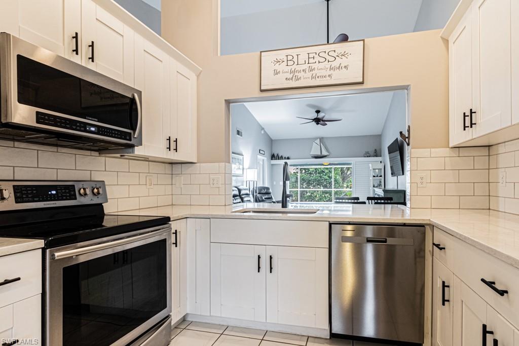 Kitchen featuring appliances with stainless steel finishes, decorative backsplash, white cabinets, and sink