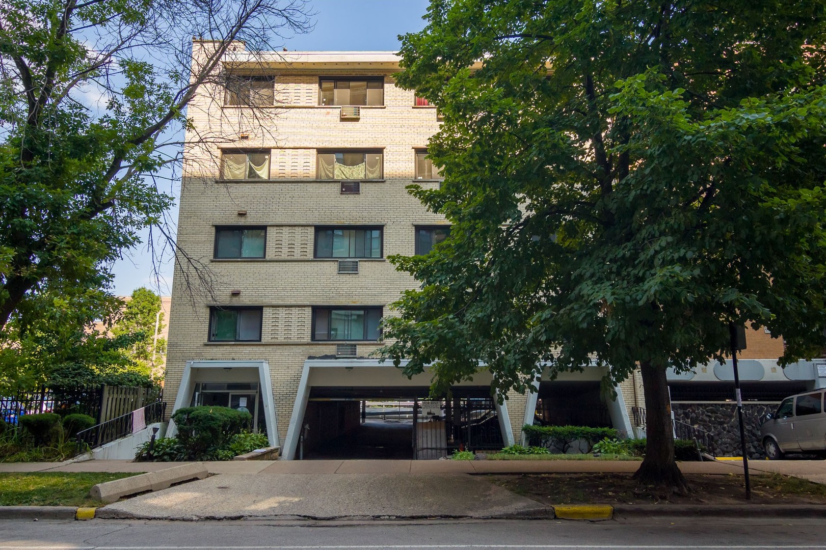 a view of a building with a yard and large trees