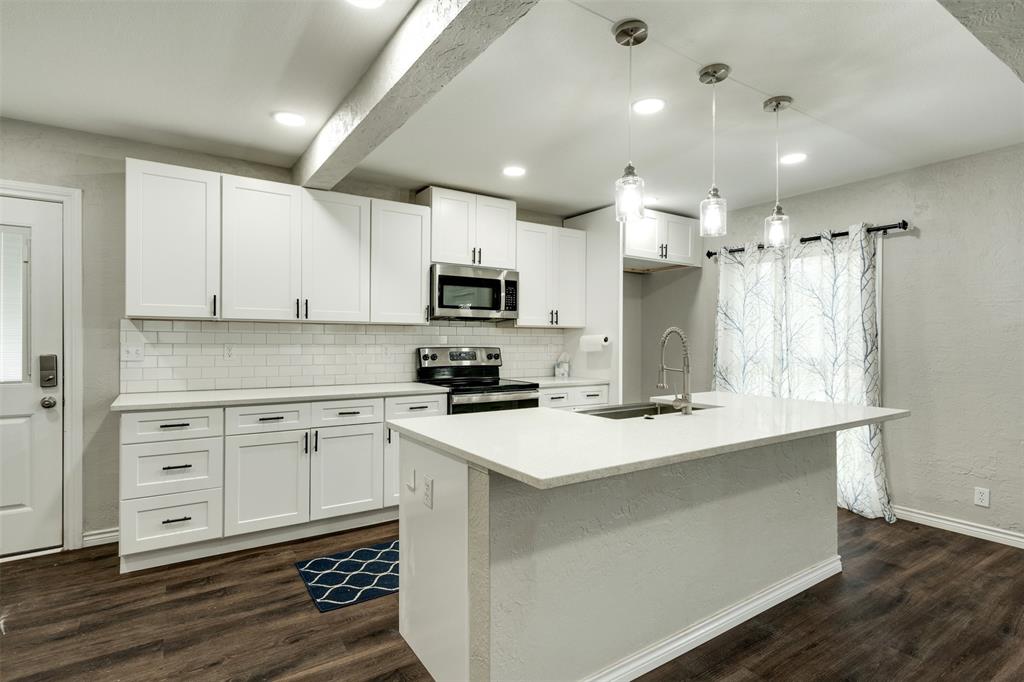 a kitchen with kitchen island a white counter top space cabinets and stainless steel appliances