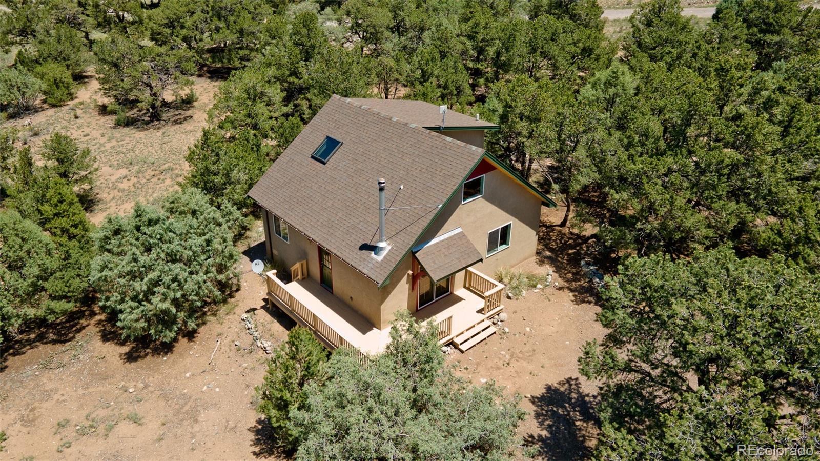 an aerial view of a house with yard and trees all around