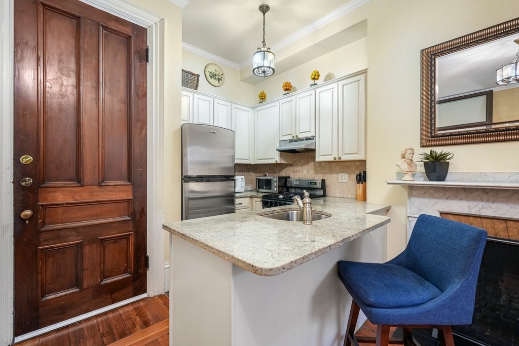 a kitchen with granite countertop a table chairs stove and refrigerator