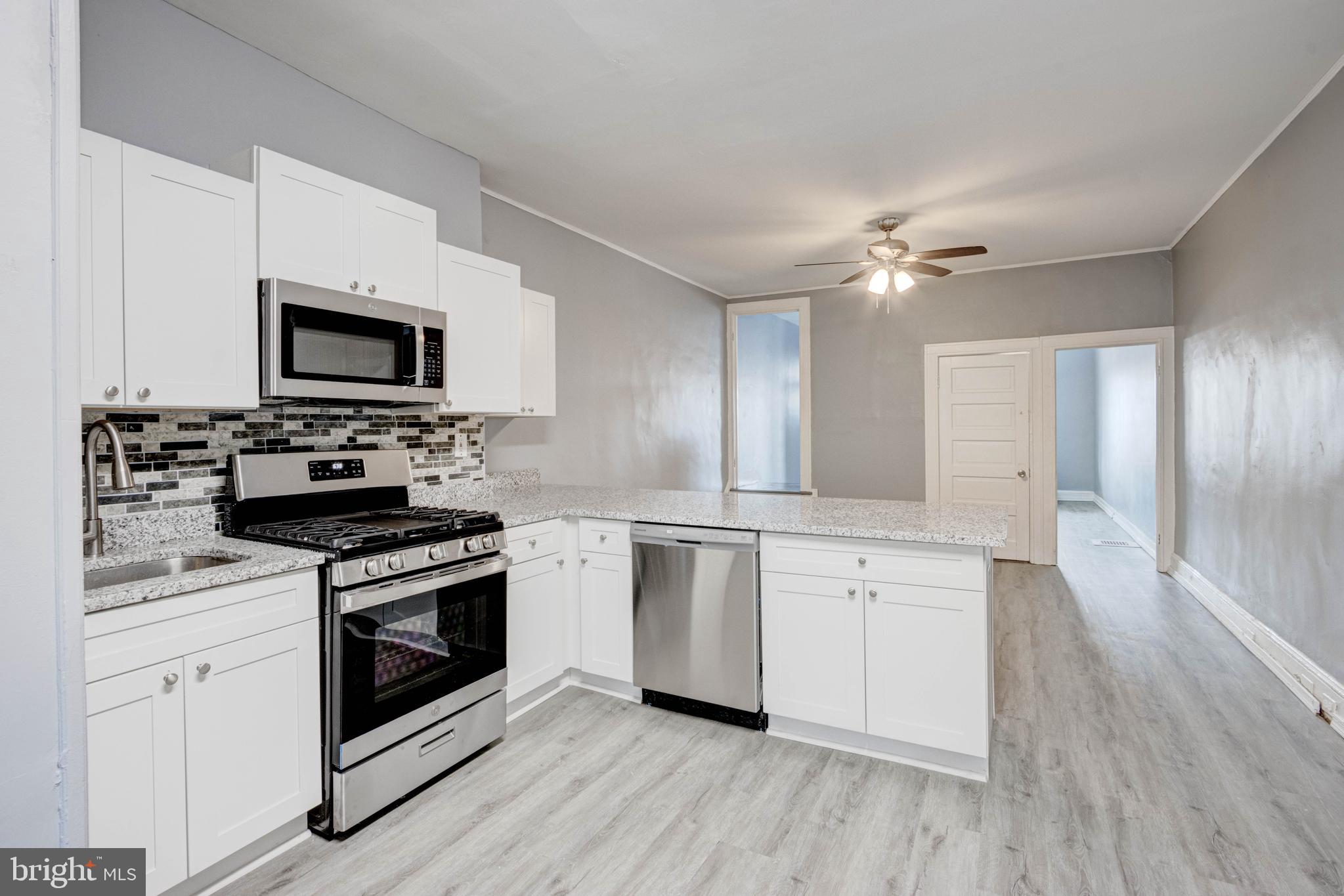 a kitchen with cabinets stainless steel appliances and wooden floor