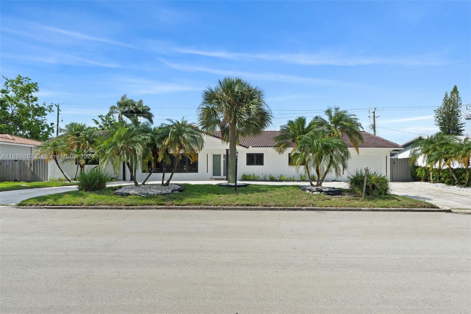 a view of a house with a yard and palm trees