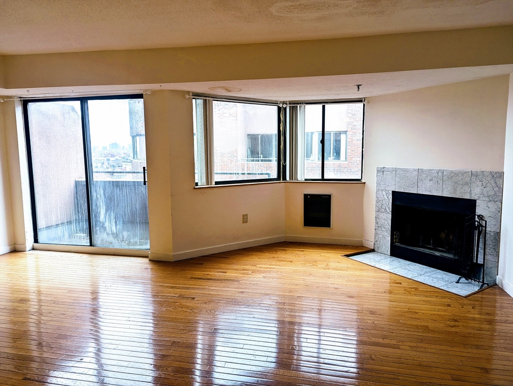 a view of empty room with wooden floor and a fireplace