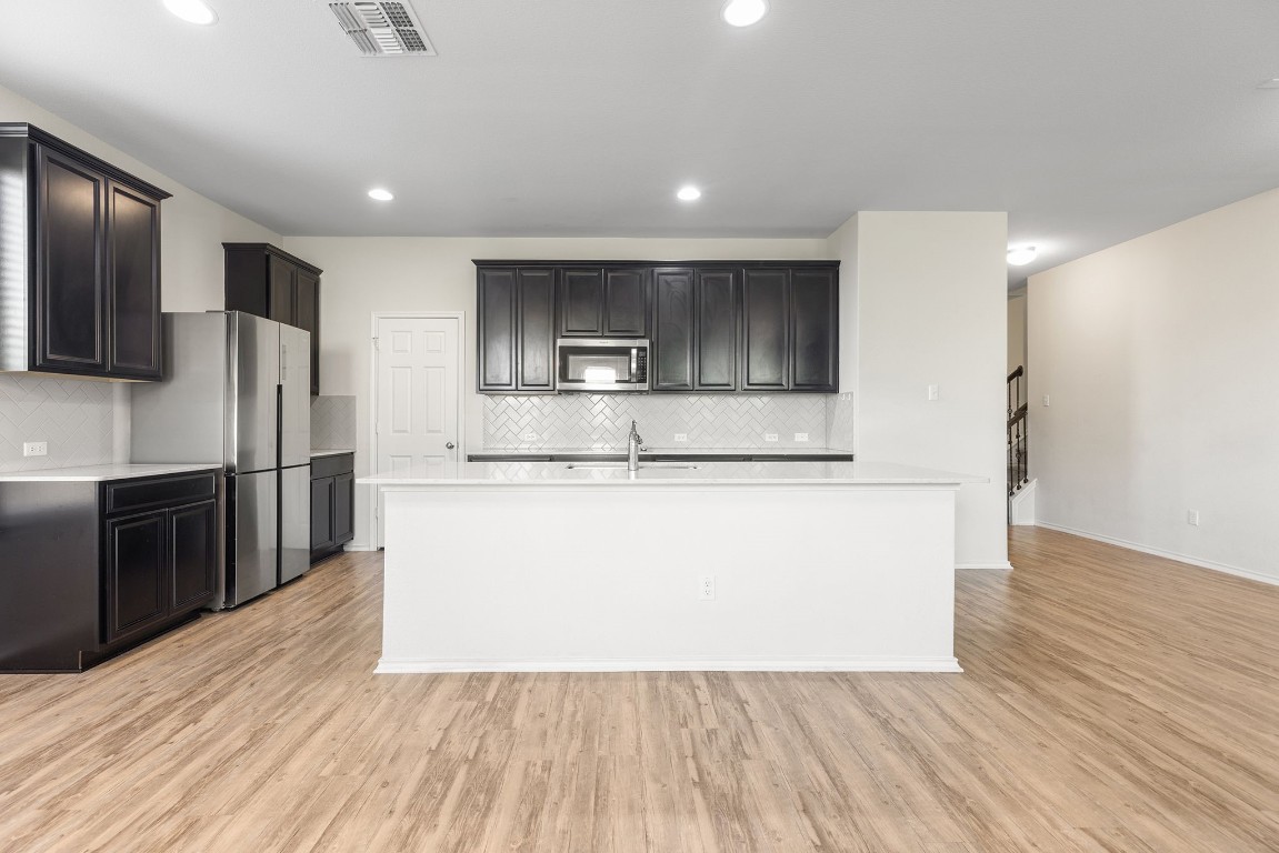 a view of kitchen with stainless steel appliances wooden floor and living room view