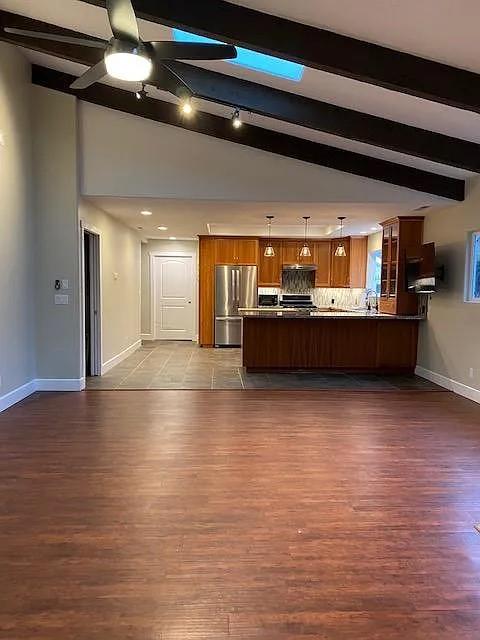 a view of a living room with kitchen island stainless steel appliances wooden floor and view living room