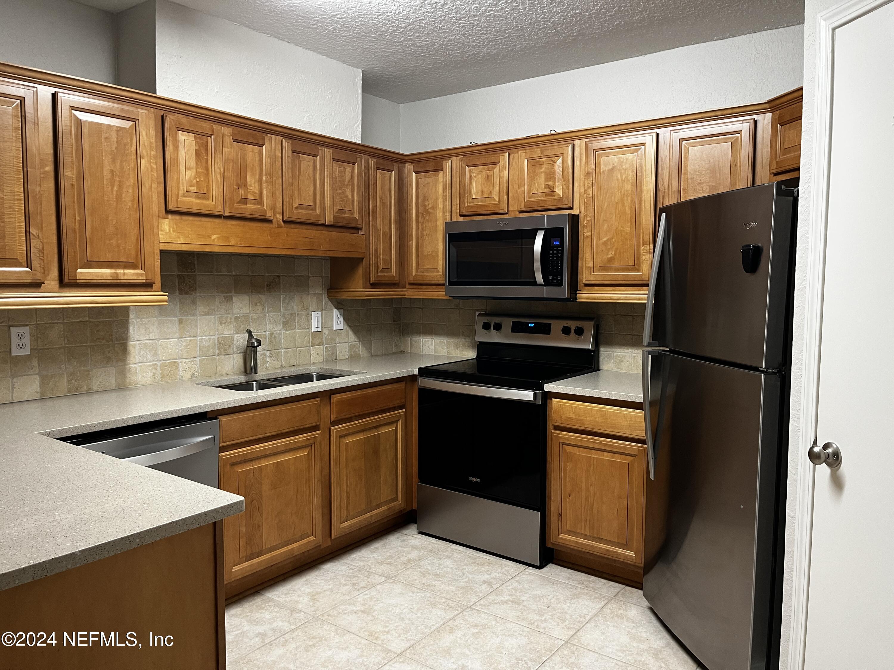 a kitchen with granite countertop a refrigerator stove top oven and sink