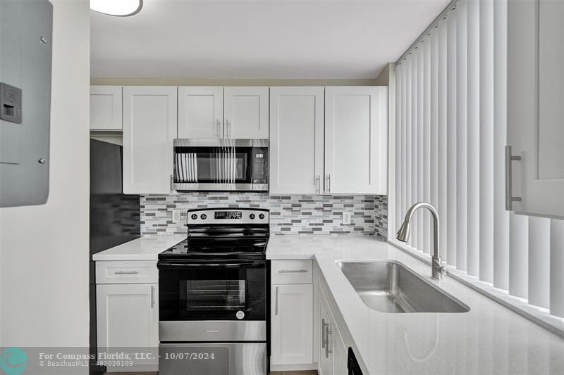 a kitchen with white cabinets a sink and stainless steel appliances