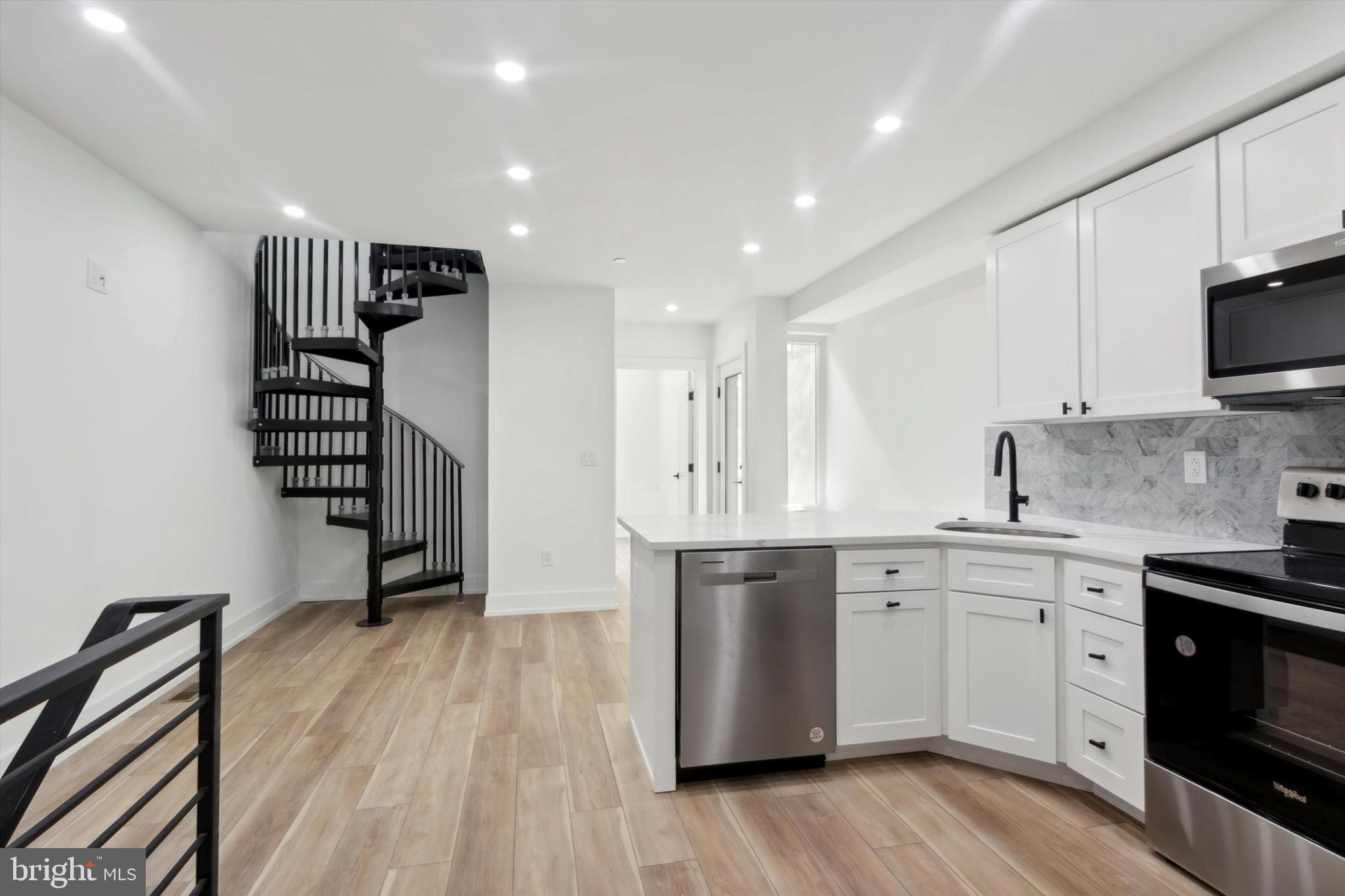 a kitchen with stainless steel appliances a sink cabinets and wooden floor