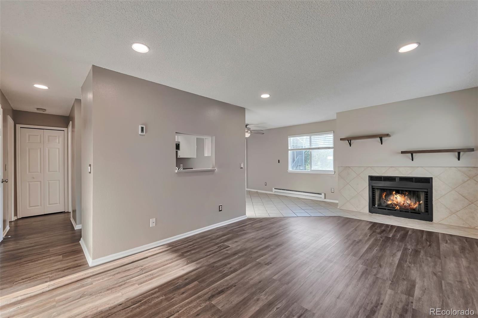 a view of an empty room with wooden floor fireplace and a window