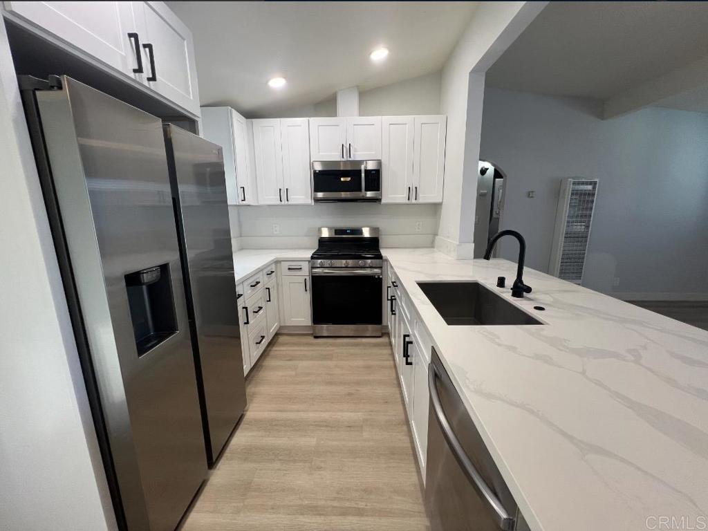 a kitchen with stainless steel appliances a sink a stove a refrigerator and cabinets