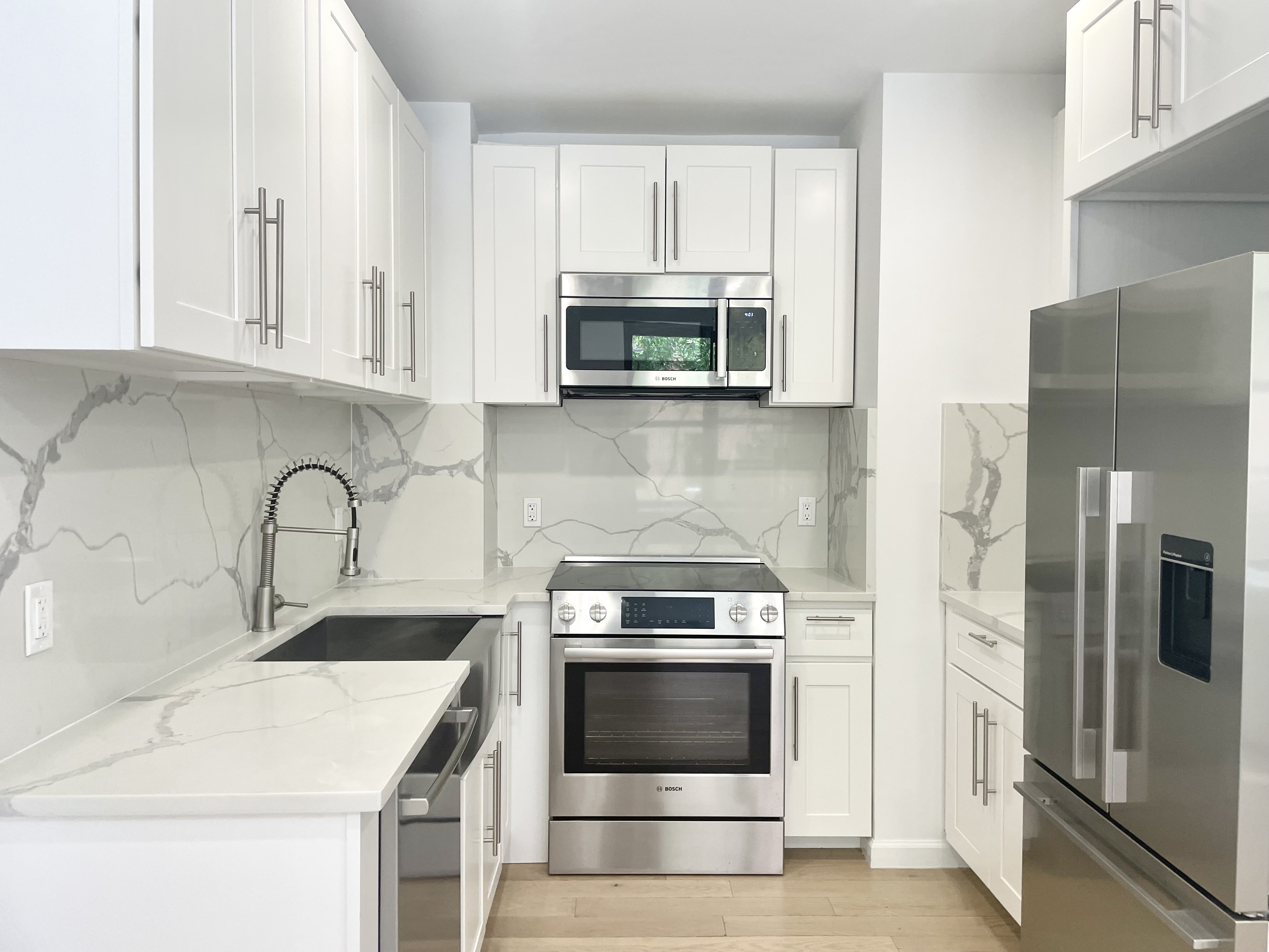 a kitchen with stainless steel appliances granite countertop white cabinets a sink a stove and a refrigerator