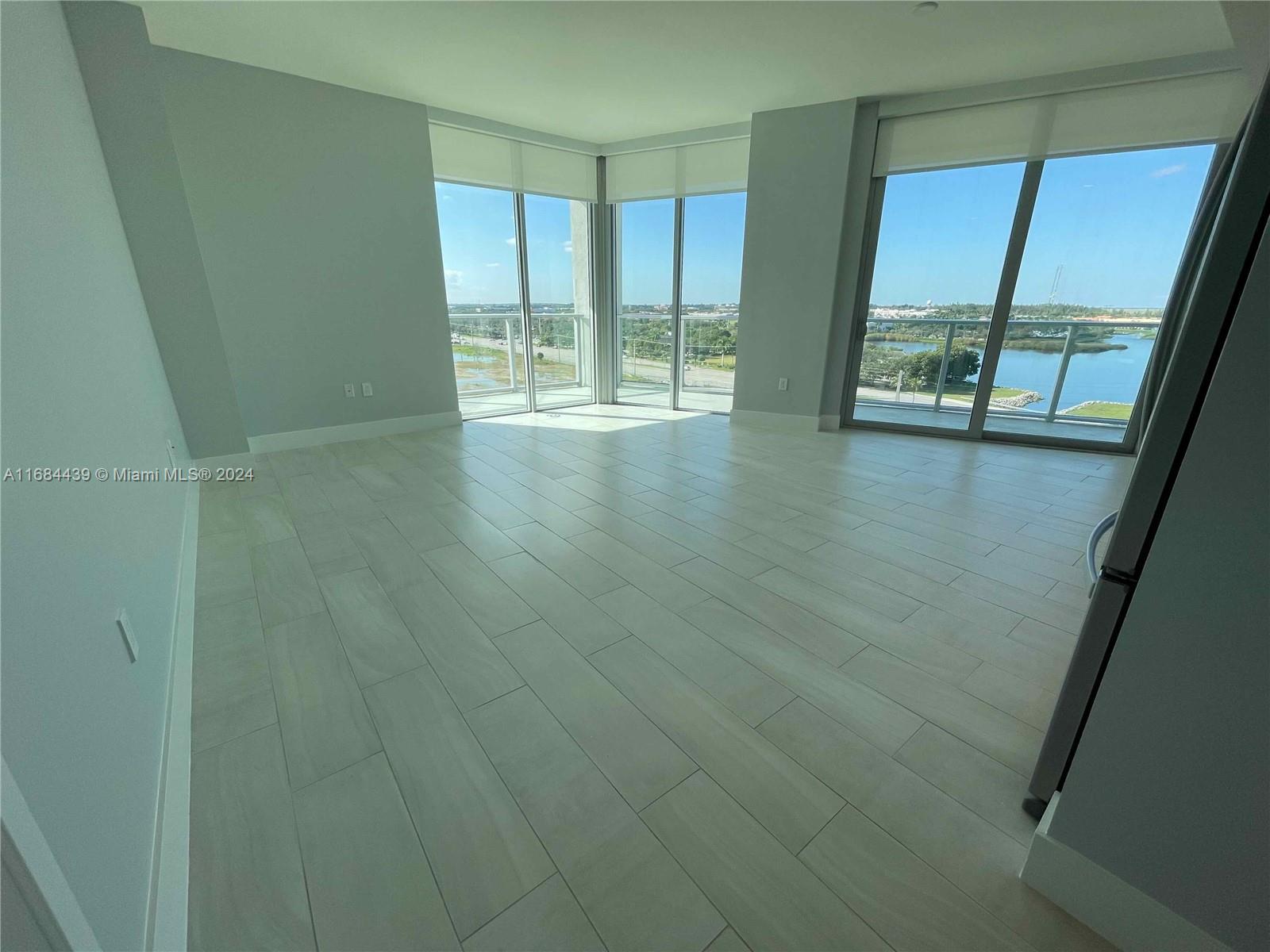 a view of an empty room with wooden floor and fan